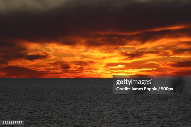 scenic view of sea against dramatic sky during sunset - james popple stock pictures, royalty-free photos & images