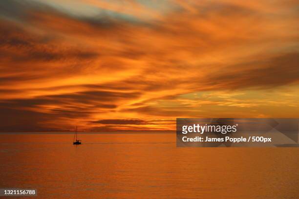 scenic view of sea against orange sky - james popple stock-fotos und bilder