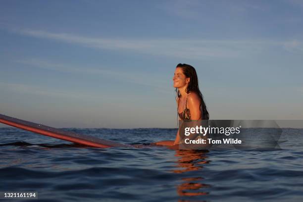 young woman seated on her surfboard - nosara stock-fotos und bilder