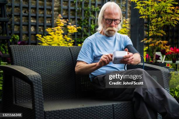 senior man self checking blood pressure - senior man grey long hair stock pictures, royalty-free photos & images