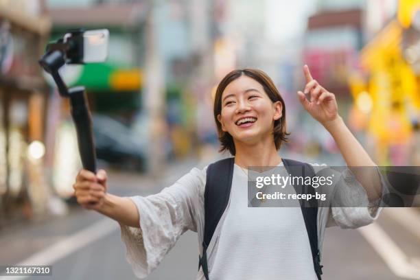 young woman vlogging with smart phone in city - the weekend in news around the world imagens e fotografias de stock