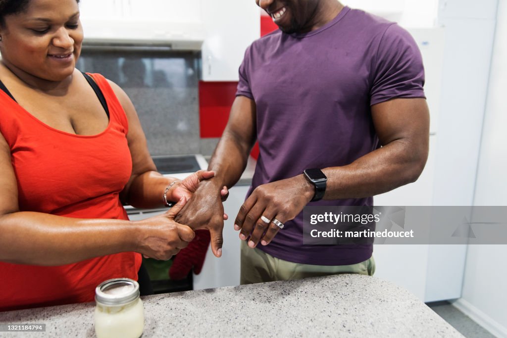 Mulher positiva do corpo esfregando creme caseiro nas mãos do marido.