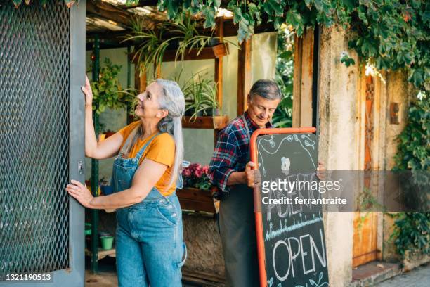 senior couple opening small business - opening event stock pictures, royalty-free photos & images