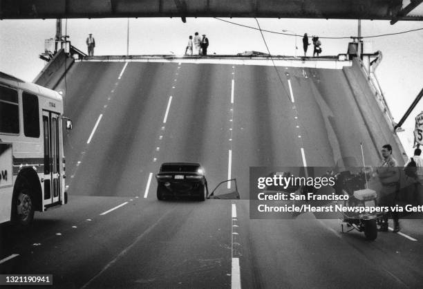 An hour after the quake, police and bridge workers deal with two cars have fallen into the gap created by the fallen span of roadway on the Bay...