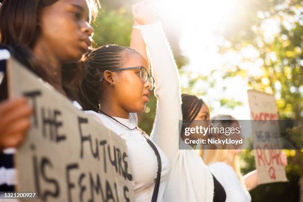diverse tienermeisjes die handen tijdens een mars van de rechten van vrouwen houden - womens day stockfoto's en -beelden