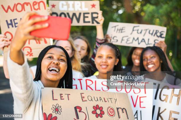 glimlachende tiener vrouwelijke vrienden die selfies nemen tijdens een mars van de rechten van vrouwen - womens day stockfoto's en -beelden