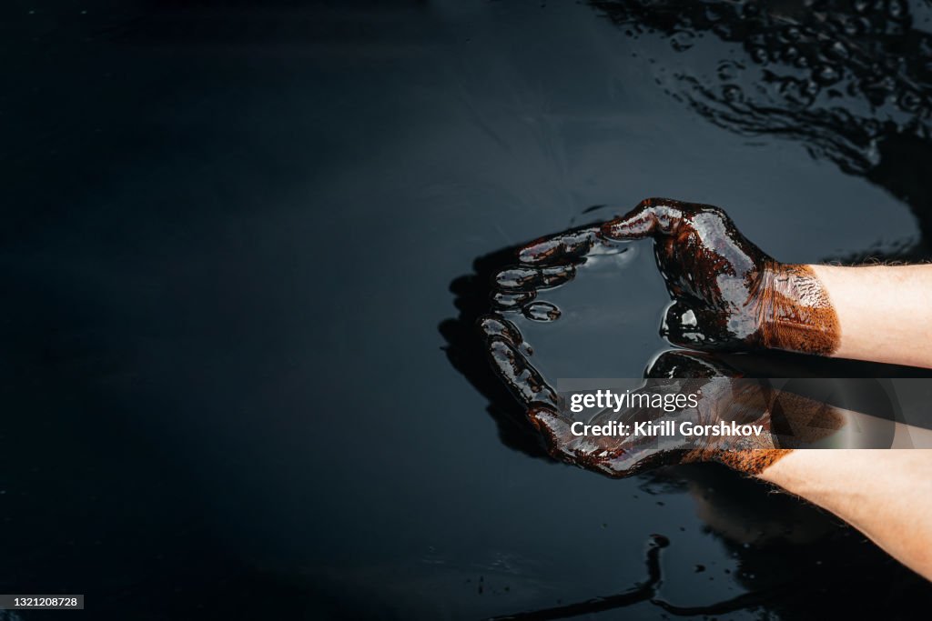 Kaukasische Ölhände werden in einer Schüssel mit Öl gefaltet. Ölpest. Umweltverschmutzung. eine Umweltkatastrophe. Kopierraum