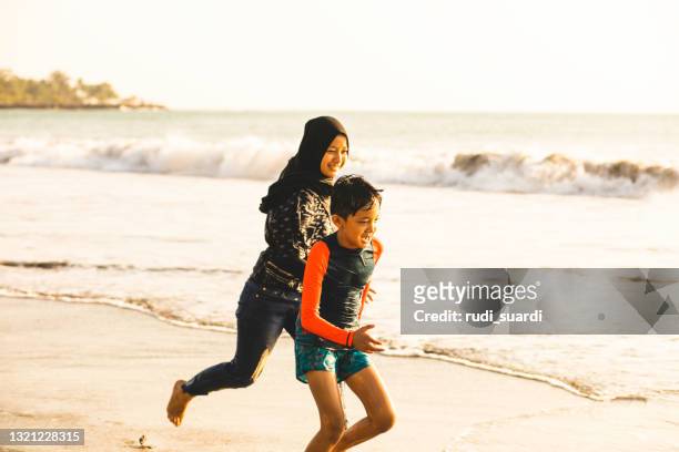 family running on the beach - muslim woman beach stock pictures, royalty-free photos & images