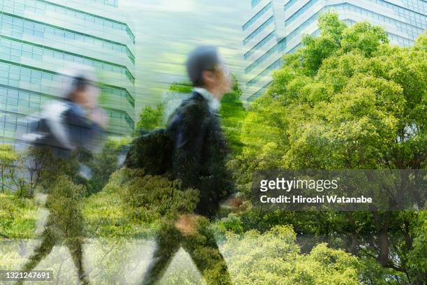 businessmen walking through full of greenery office district multi layered image - mehrfachbelichtung bewegung stock-fotos und bilder