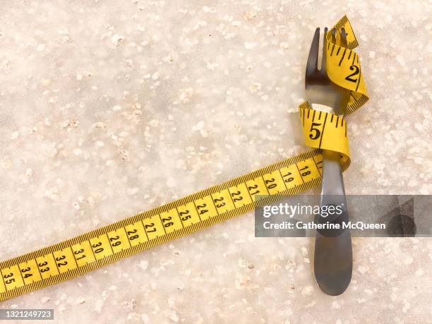 silver fork intertwined with flexible tape measure - anorexie nerveuse photos et images de collection