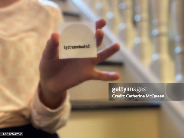 mixed-race teen girl holds a covid-19 vaccination sticker - vaccine sticker stock pictures, royalty-free photos & images