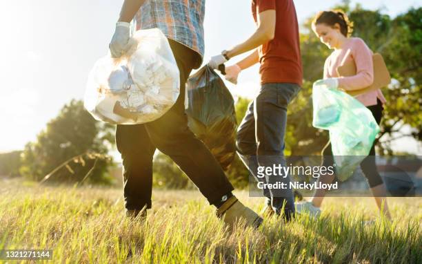diverse group of volunteers walking in a field during a cleanup day - volunteers cleaning public park stock pictures, royalty-free photos & images
