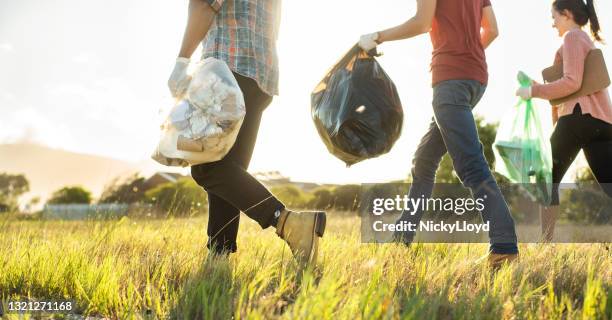 jonge vrijwilligers die op een gebied tijdens een opruimdag lopen - collection stockfoto's en -beelden