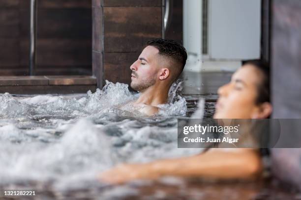 man chilling near girlfriend in massage pool - luxury spa stock pictures, royalty-free photos & images