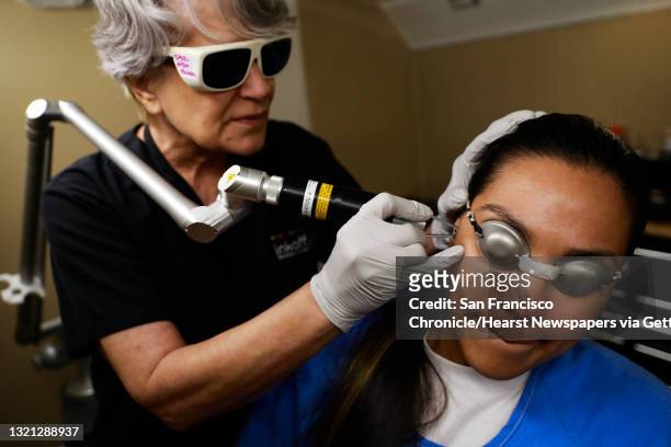 Barbara Schach lasers inmate Jessica Garcia's face as she grimaces while undergoing a laser tattoo removal treatment through Inkoff.me at the Folsom...