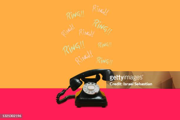 horizontal front view of an antique black dial telephone on a multicolored background. the handset is moving and "ring" signs appear. - llama fotografías e imágenes de stock