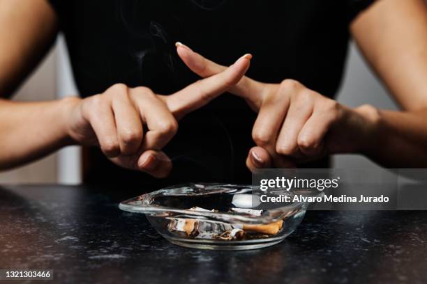 unrecognizable young woman refusing smoking with an ashtray full of cigarette butts in front of her. - aschenbecher stock-fotos und bilder