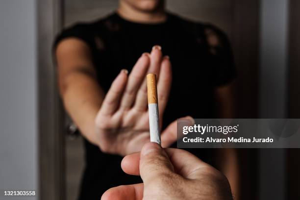 hand of unrecognizable young woman refusing a tobacco cigarette to try to quit smoking. - stopschild stock-fotos und bilder