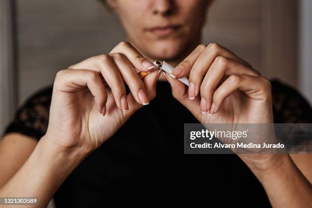unrecognizable young woman breaking a cigarette in half to stop smoking. - femme et fumeuse photos et images de collection
