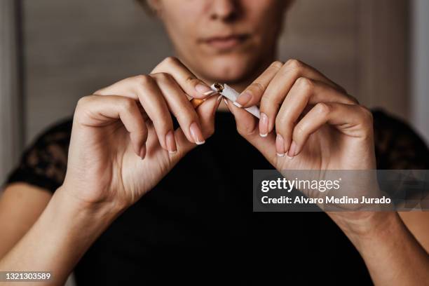 unrecognizable young woman breaking a cigarette in half to stop smoking. - produto relacionado com tabaco - fotografias e filmes do acervo