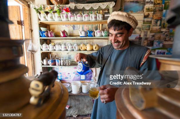 a man working in a traditional old tea shop in istalif near kabul pours hot tea into a glass - afghan old man stock pictures, royalty-free photos & images