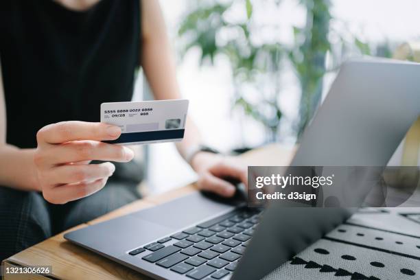 close up of mid-section of young asian woman relaxing in cafe, shopping online using laptop and making mobile payment with credit card on hand. lifestyle and technology. comfortable and fast online shopping experience - online payments stock pictures, royalty-free photos & images