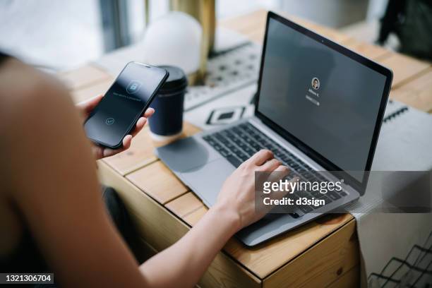 young businesswoman working on desk, logging in to her laptop and holding smartphone on hand with a security key lock icon on the screen. privacy protection, internet and mobile security concept - security photos et images de collection