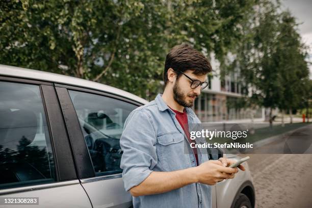 junger mann mit telefon, während auf freund warten - fachmann auto smartphone stock-fotos und bilder