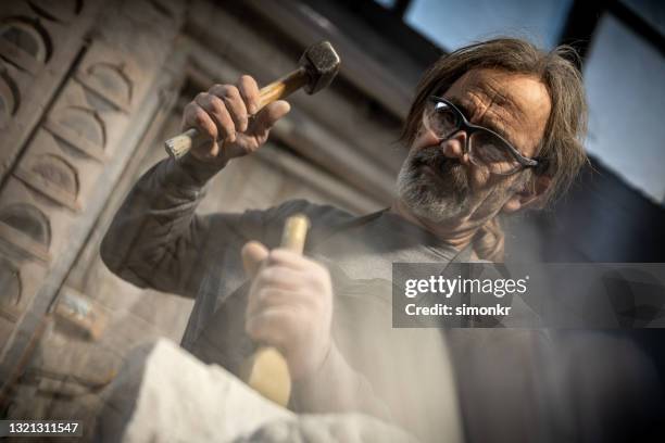 stonemason carving a sculpture in the workshop - sculpture stock pictures, royalty-free photos & images