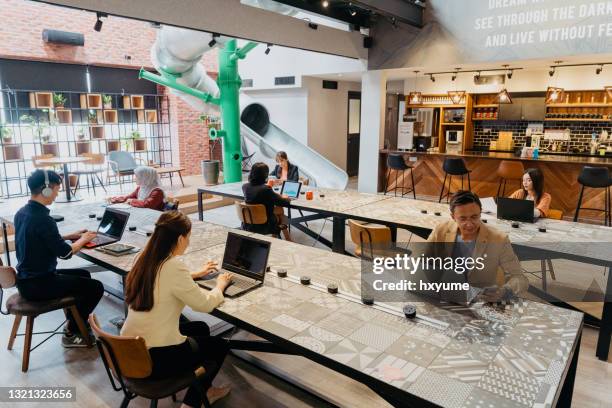 diverse aziatische mensen die in co-working ruimte werken - flexplekken stockfoto's en -beelden