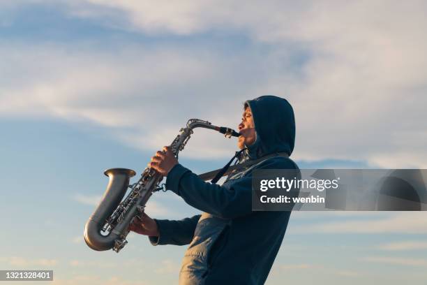 a saxophone player is playing by the sea - saxophoniste photos et images de collection