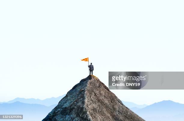 geschäftsmann auf dem gipfel des berggipfels hält große flagge - erwartung stock-fotos und bilder