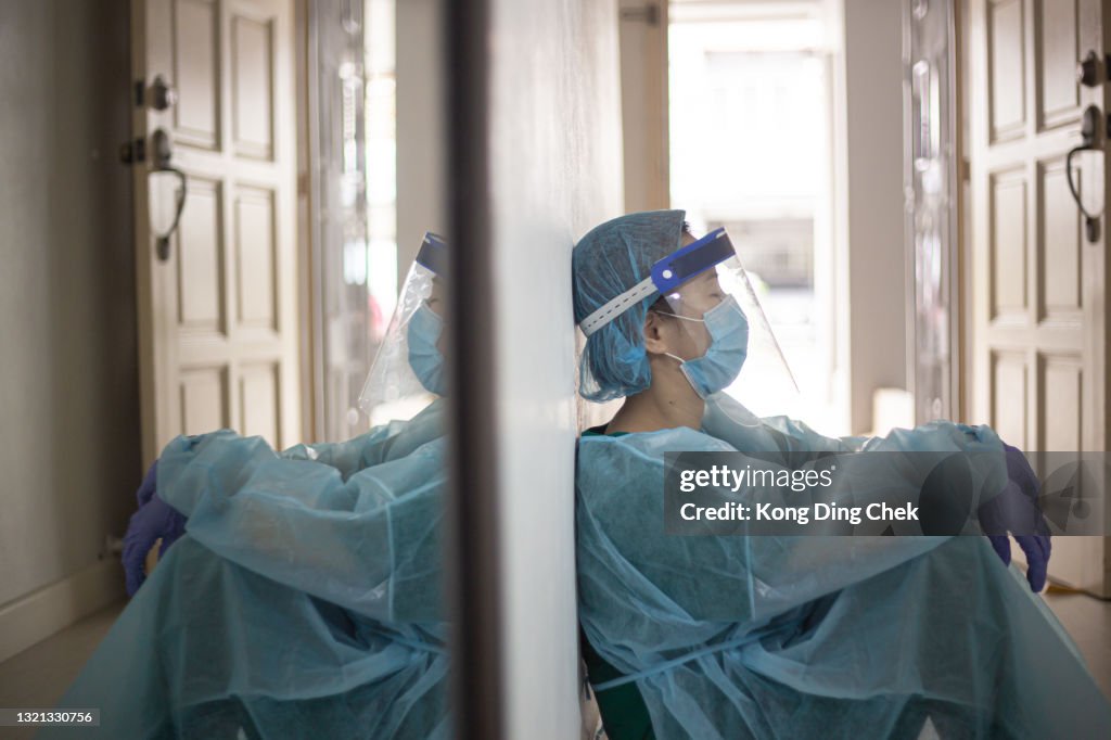 Asiatische chinesische weibliche Frontliner müde sitzen auf dem Boden während Pandemic