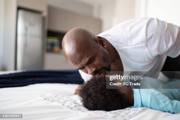 pai colocando filho dormindo na cama em casa - good night kiss - fotografias e filmes do acervo
