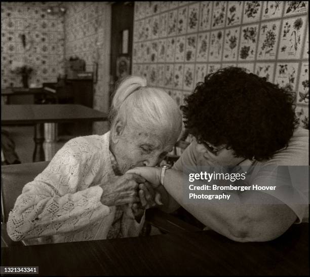 View of an elderly woman as she kissed the hand of a caregiver in a nursing home, Glendale, California, 1982.