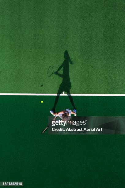 drone shot above a female tennis player and her shadow, england, united kingdom - match sport stock-fotos und bilder