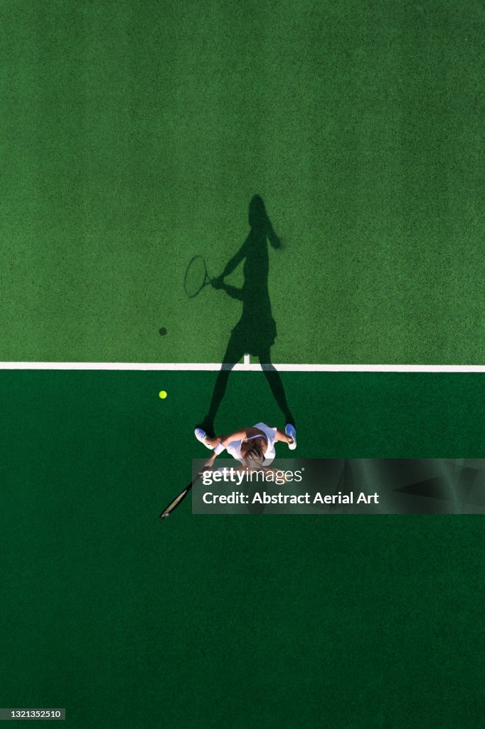Drone shot above a female tennis player and her shadow, England, United Kingdom