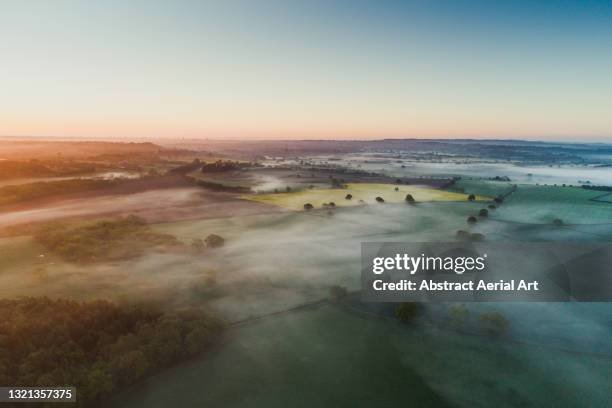 aerial shot showing a low level mist at sunrise over the english countryside, england, united kingdom - rural landscape stock-fotos und bilder