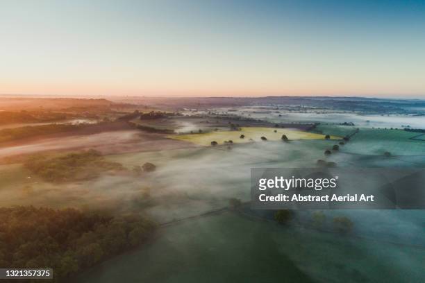 aerial shot showing a low level mist at sunrise over the english countryside, england, united kingdom - light natural phenomenon foto e immagini stock