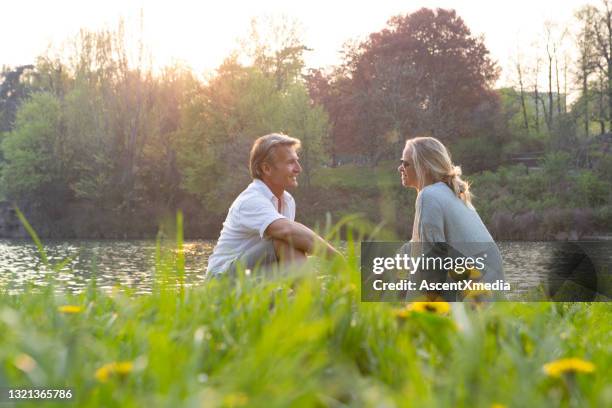 rijp paar ontspant in weide, boven rivier - rivier gras oever stockfoto's en -beelden