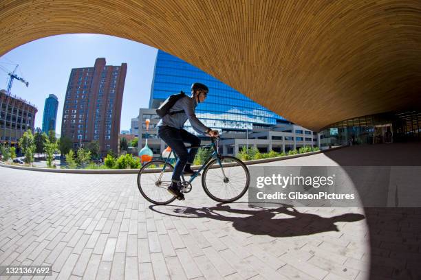 bicycle messenger outside the calgary public library - calgary summer stock pictures, royalty-free photos & images