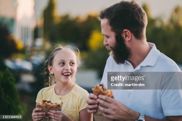 vater mit tochter essen fast food - burger portrait stock-fotos und bilder