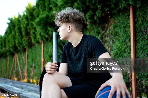 young basketball player sitting on the bench - reserve athlete stock pictures, royalty-free photos & images