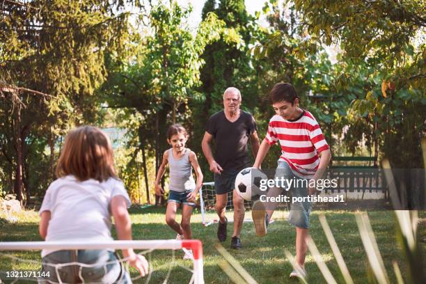 familie mit spaß und fußball im hinterhof - backyard football stock-fotos und bilder