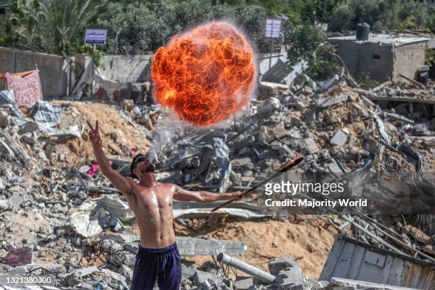 Beit Lahia, northern Gaza Strip. 26th May 2021. Palestinian youth perform fire breathing at the ruins of a building destroyed in recent Israeli air...