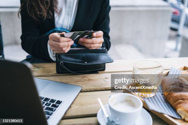 young business woman shops online at outdoor cafe - black purse stock pictures, royalty-free photos & images