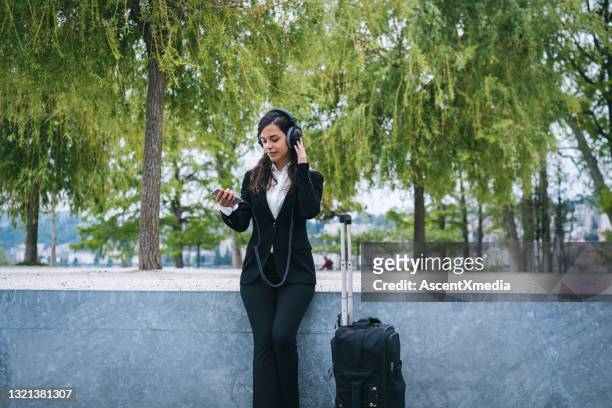 junge geschäftsfrau hört musik im stadtpark - young woman trolley stock-fotos und bilder