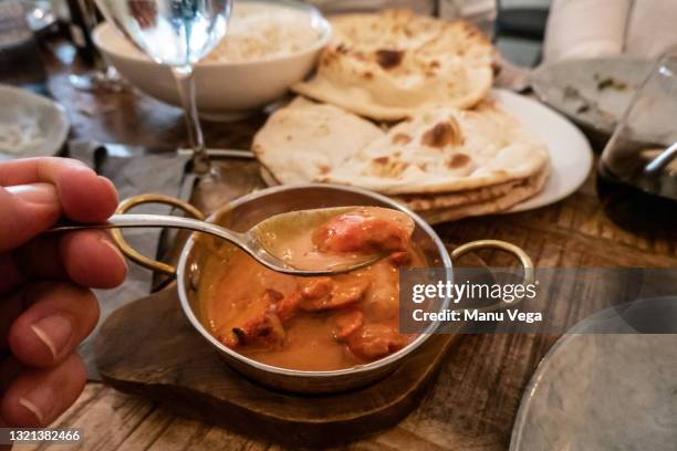 close up of indian butter murgh tikka in a silver bowl with spoon in restaurant - tikka masala stockfoto's en -beelden