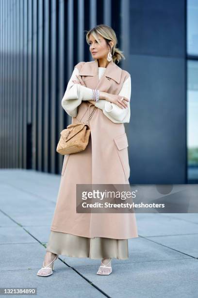 Influencer Gitta Banko wearing a long beige vest by Max Mara, a long beige silk skirt by Nanushka, a beige Pullover with cut out details by Brunello...