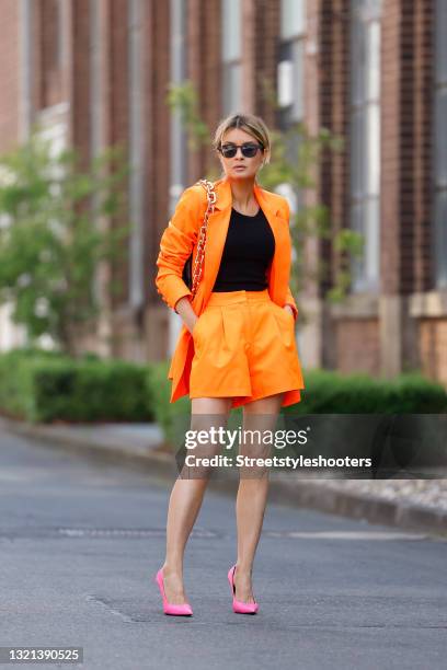 Influencer Gitta Banko wearing a neon orange blazer by Pearl And Rubies, neon orange shorts by Pearl And Rubies, a black tank top by Zara, neon pink...